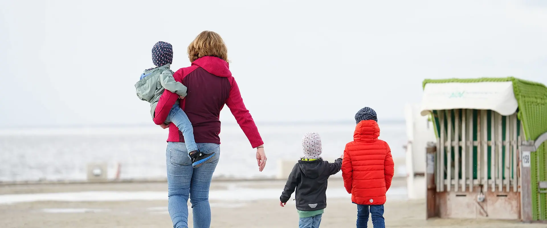 Kinder laufen mit ihrer Mutter am Strand entlang während der Mutter-Kind-Kur