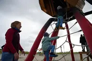 Mutter spielt mit ihren Kindern auf einem Spielplatz am Strand