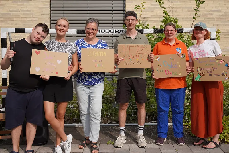 Das Bild zeigt die Menschen mit ihren Plakaten, die sie für den CSD Braunschweig gestaltet haben.