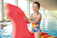 Mädchen reitet auf Wassertier im Schwimmbad