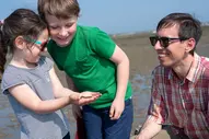 Vater spielt mit seinen beiden Kindern am Strand